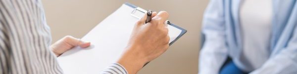 Provider taking notes during a patient consultation, representing thorough assessment and individualized care planning