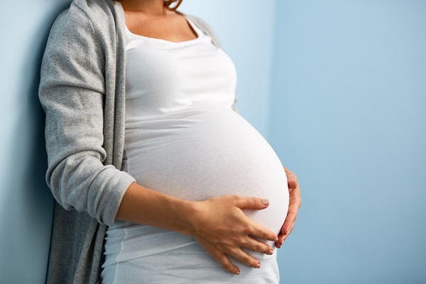 Pregnant woman holding her belly, representing prenatal chiropractic care focused on comfort, mobility, and support during pregnancy