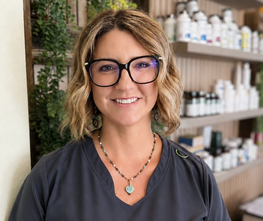 Renee wearing glasses and navy scrubs standing in a wellness clinic.
